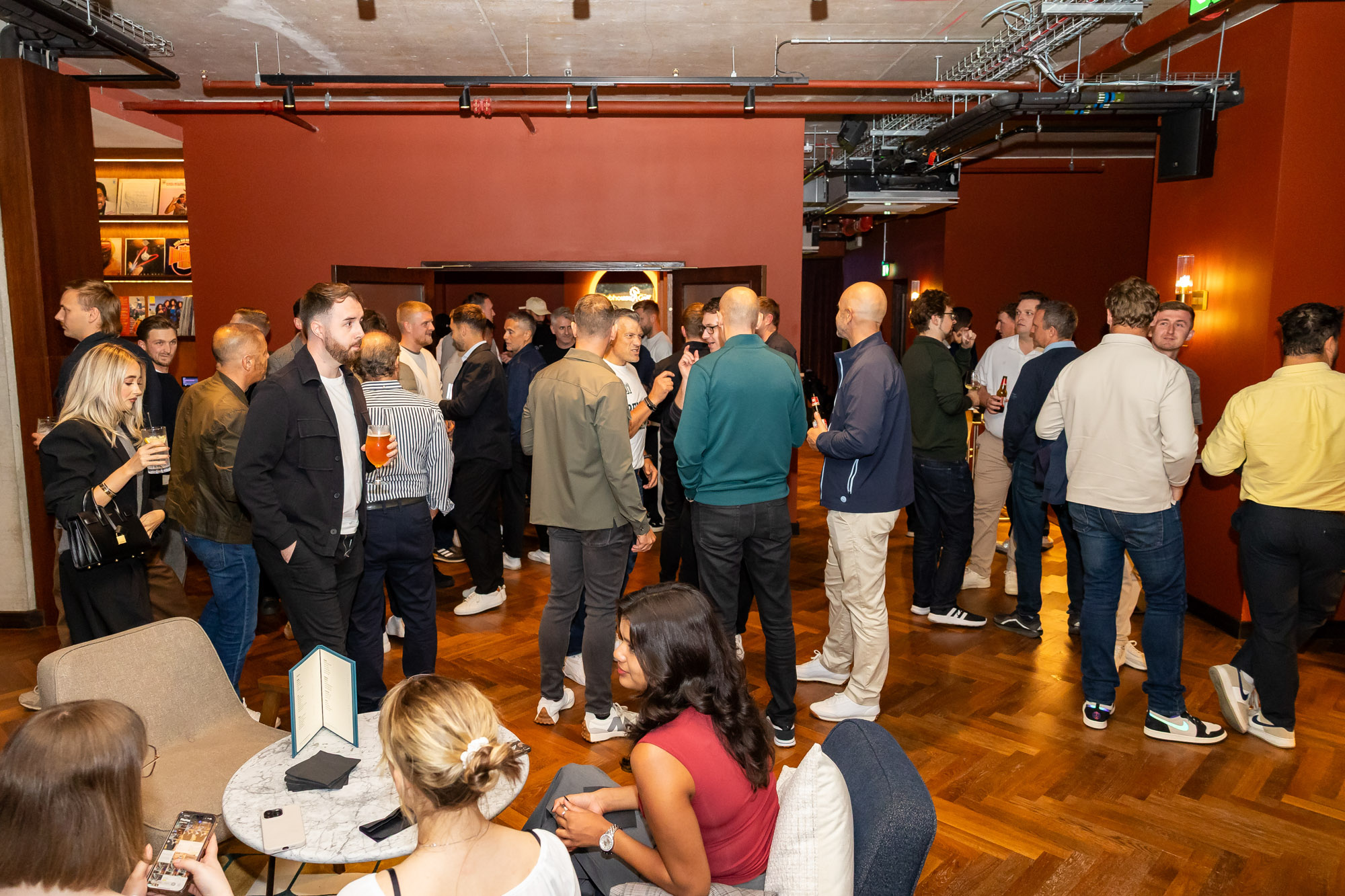Large crowd of people in the venue with some sat on lounge chairs